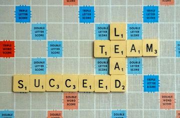 Scrabble tiles spelling Team, Lead, and Succeed